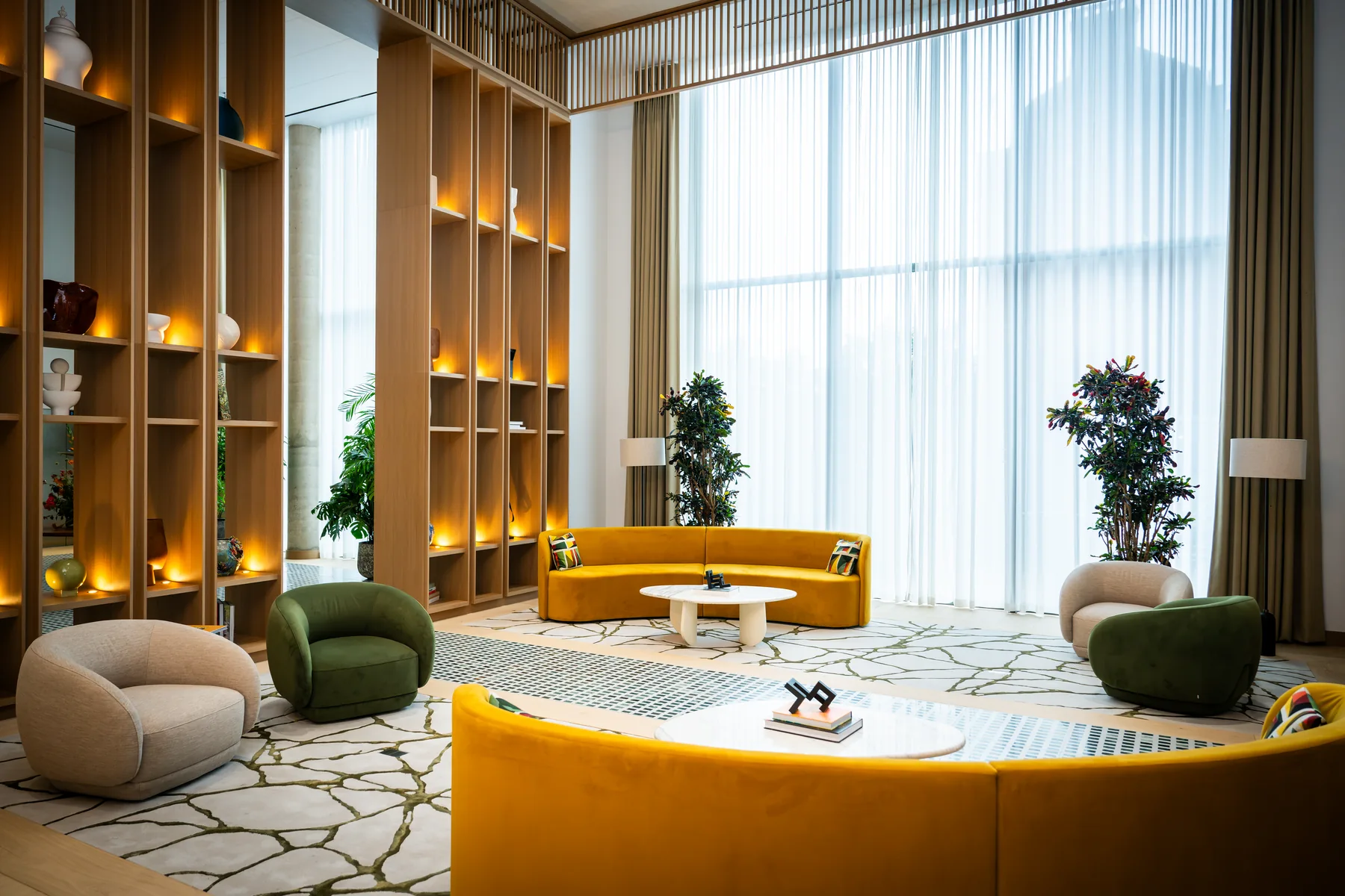 The completed arrival lounge at Hurlingham Waterfront, with yellow seating and illuminated timber shelves